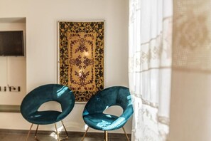 Two chairs with a unique design, a wall-mounted artwork, and a window with curtains.