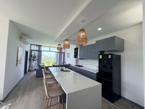 A modern kitchen with a central island, bar stools, and a view of the outdoors.
