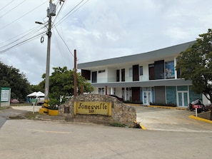 A building with a stone entrance sign, a pharmacy, and a bike rental service. - Retreat with views of the mountains and the sea - Roatán (Jonesville)
