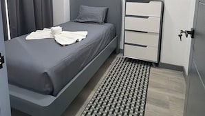 Ein modernes Schlafzimmer mit einem Bett, einem Nachttisch mit Lampe und einem gemusterten Teppich.