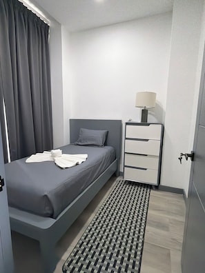 A modern bedroom with a bed, a bedside table with a lamp, and a patterned rug. - Retreat with views of the mountains and the sea - Roatán (Jonesville)