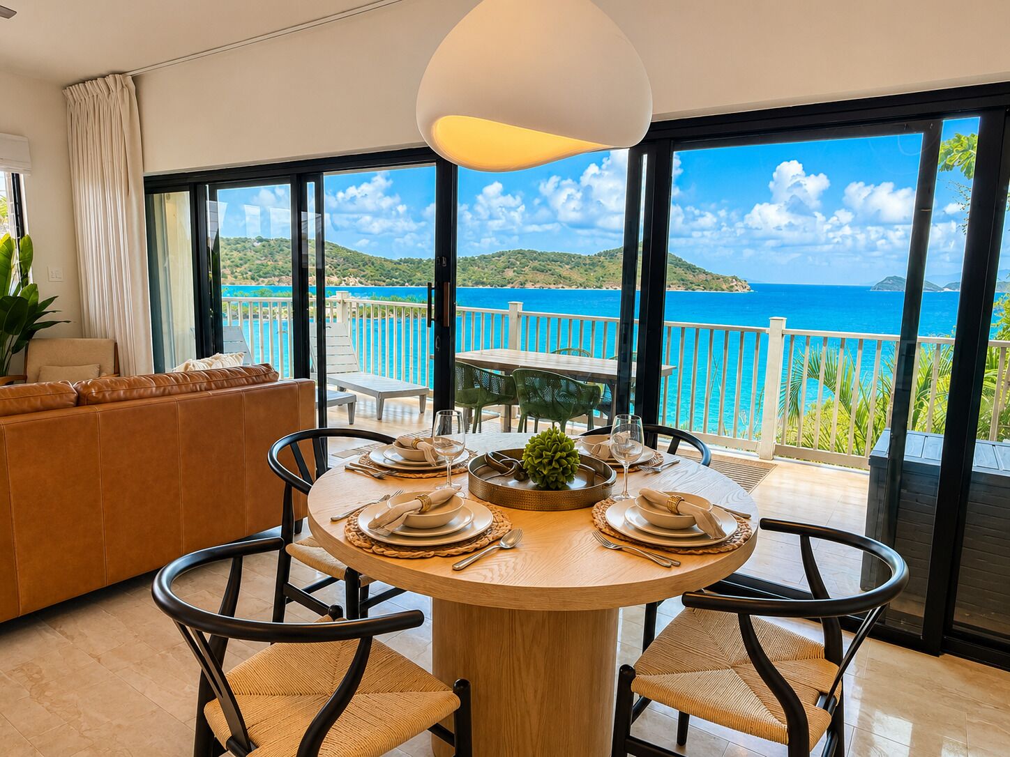 Un comedor con una mesa dispuesta para cuatro, con vistas panorámicas del mar y las colinas.