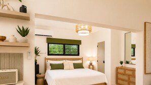A bedroom with a bed, bedside table, lamp, dresser, mirror, and a window with blinds. - Panoramic Caribbean views at Villa Orizzonte (St Thomas)
