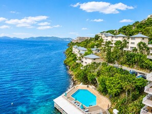 A coastal resort with a swimming pool, beachfront villas, and a view of the sea.