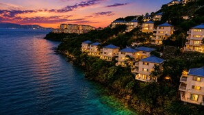 A coastal residential area with multiple buildings, some with balconies, overlooking a body of water. - Panoramic Caribbean views at Villa Orizzonte (St Thomas)