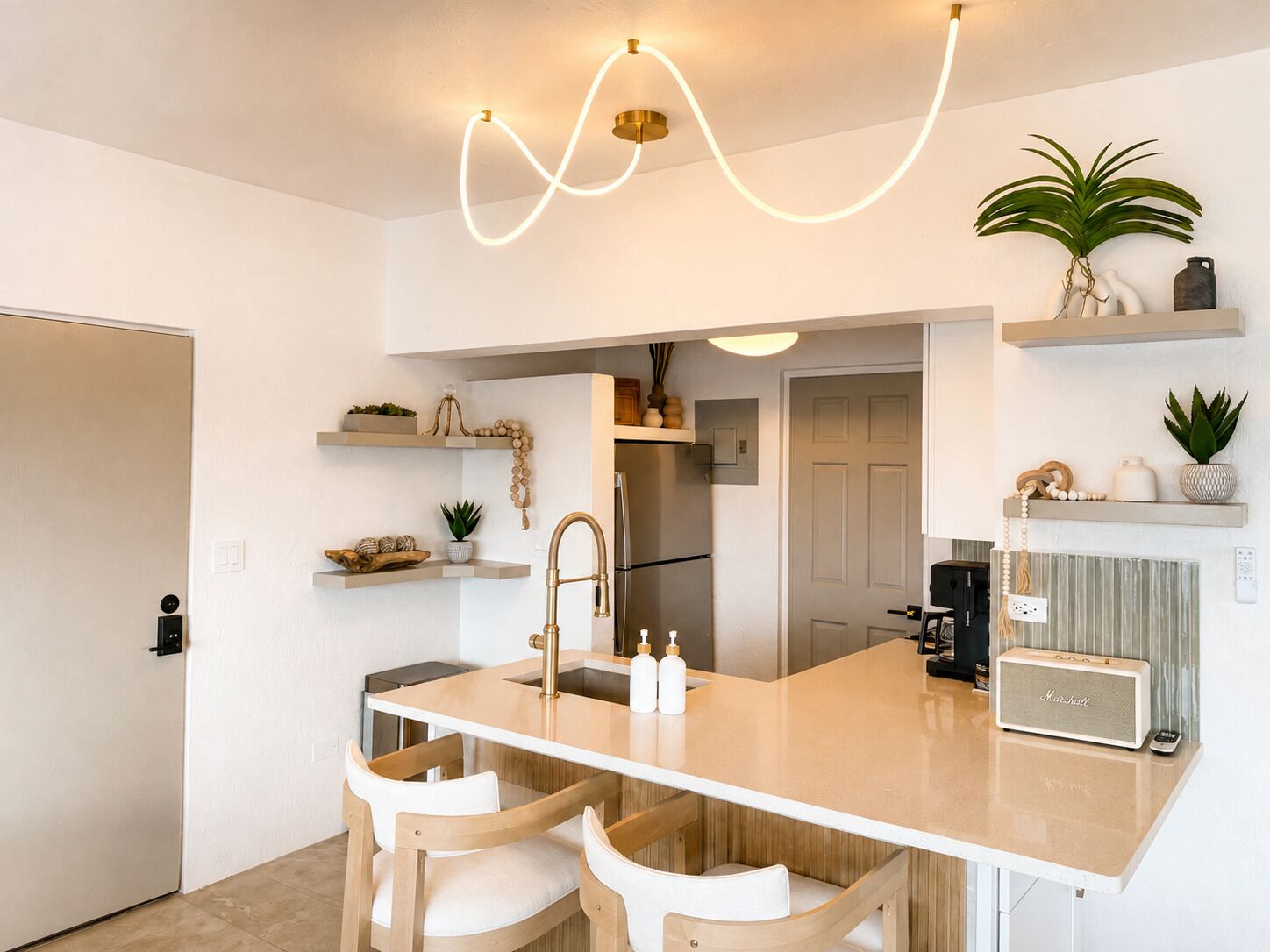 Een moderne keuken met een centraal eiland, barstoelen en een ingebouwde radio.