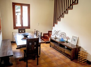 Ein Essbereich mit Holztisch und -stühlen, einer Treppe und einem kleinen Regal mit Dekoration.
