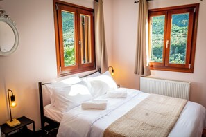 Una camera da letto con un letto, due lampade da comodino, un termosifone e due finestre con tende.