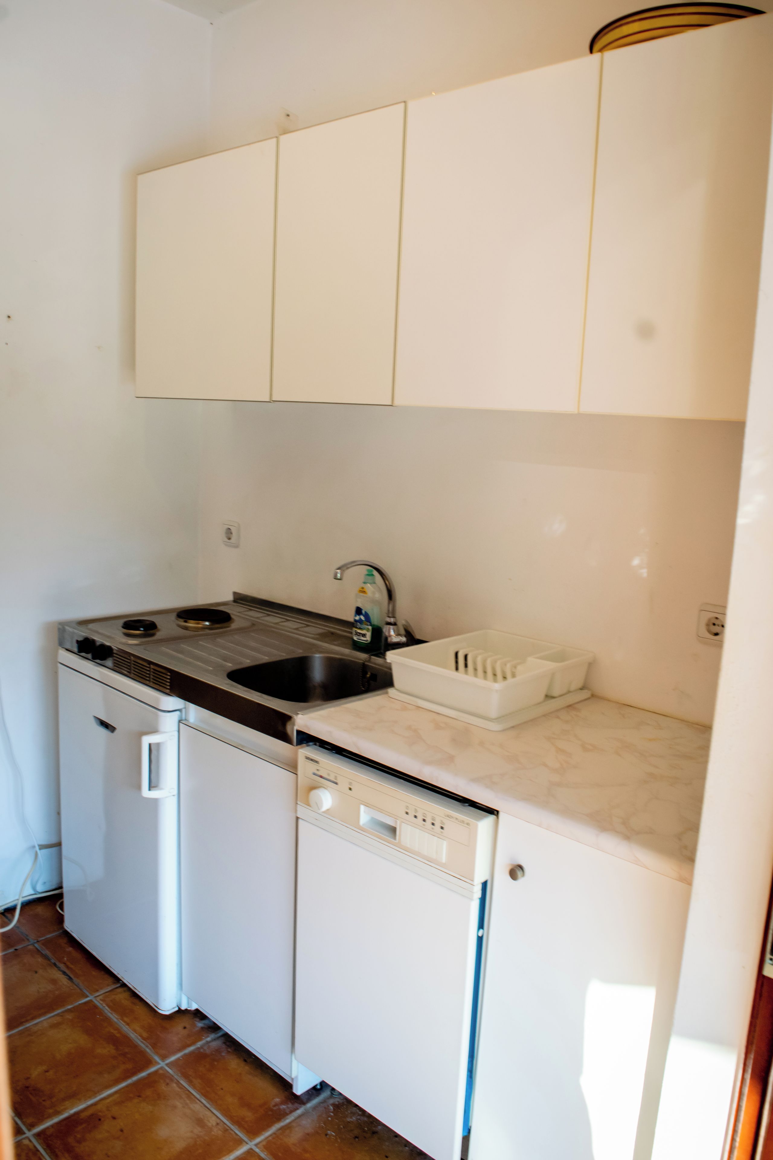 A compact kitchen with white cabinets, a sink, a stove, and a dishwasher.