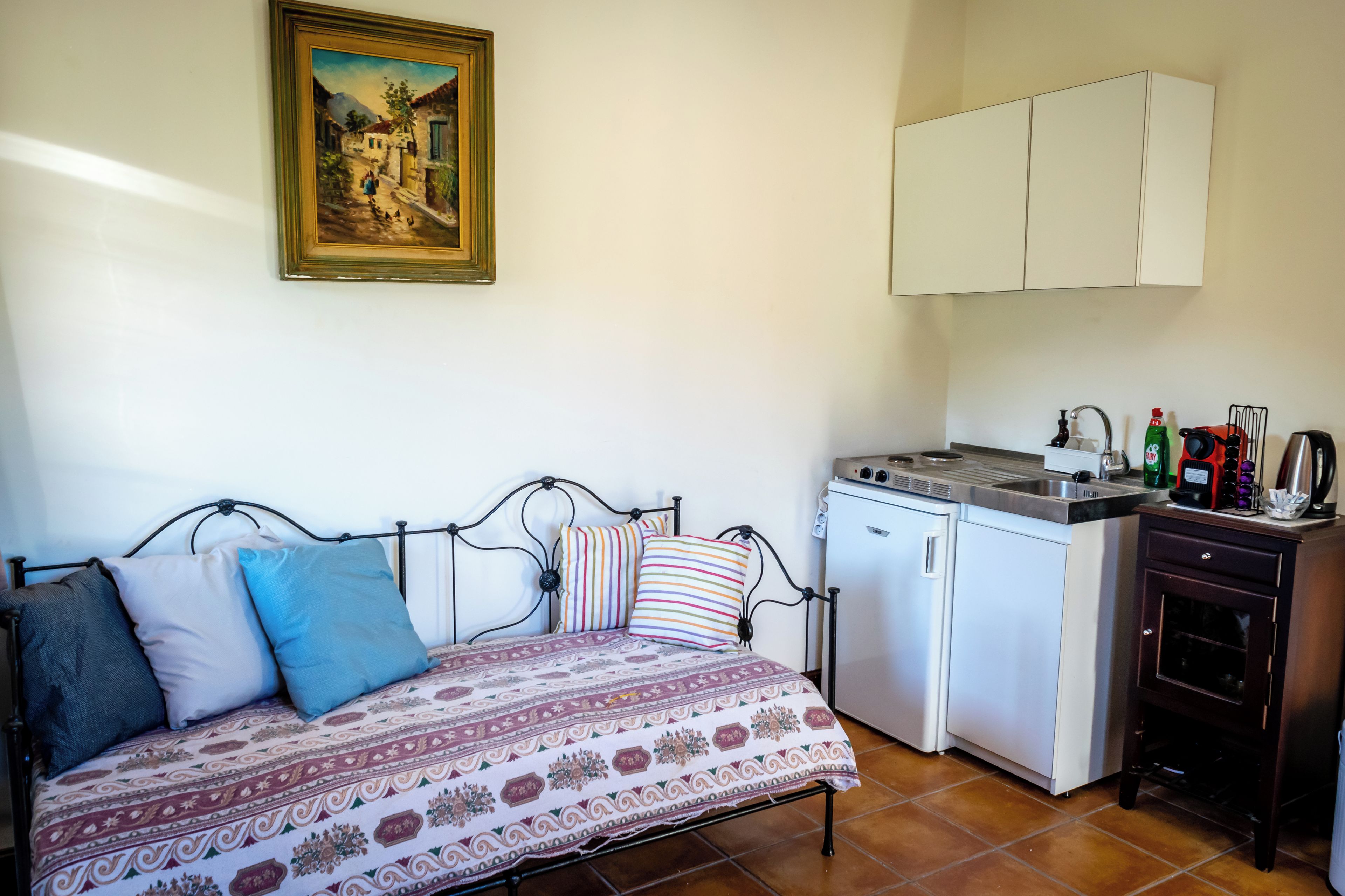 A small, cozy room with a bed, a washing machine, and a kitchenette.