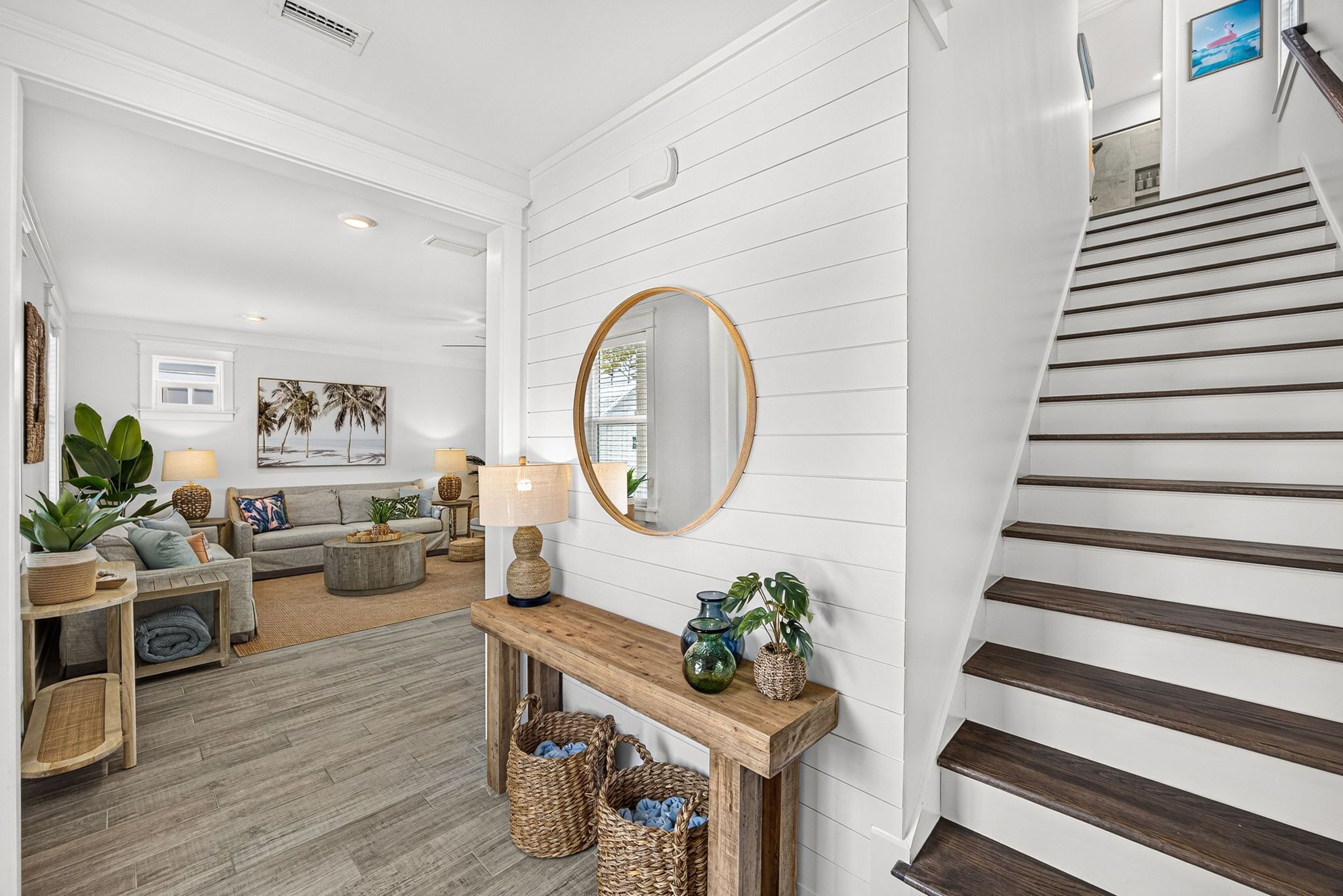 A modern living room with a staircase, wooden flooring, and a console table with decorative items.