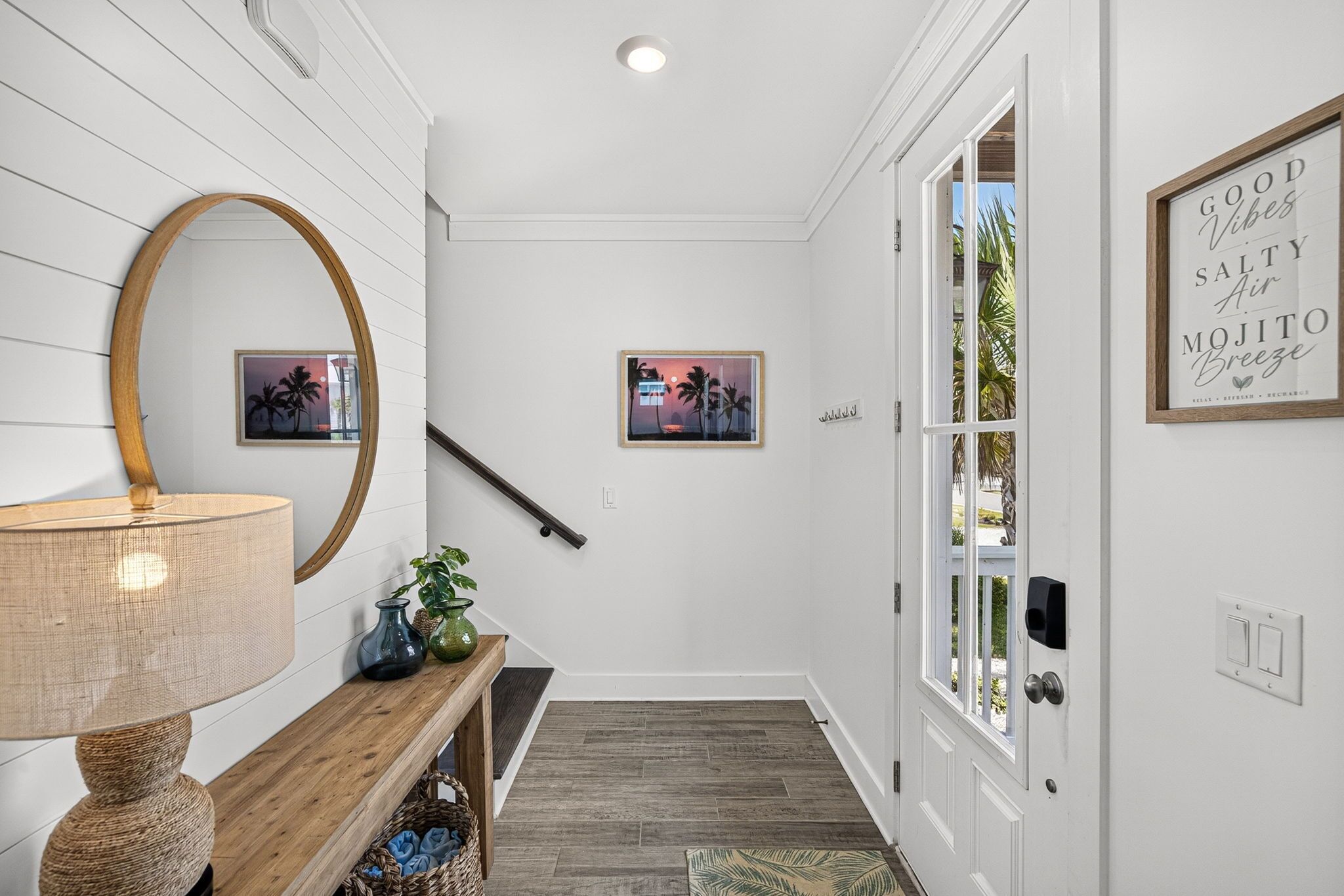 A hallway with a wooden bench, a lamp, and two framed pictures on the wall.