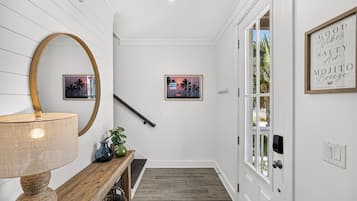 A hallway with a wooden bench, a lamp, and two framed pictures on the wall.