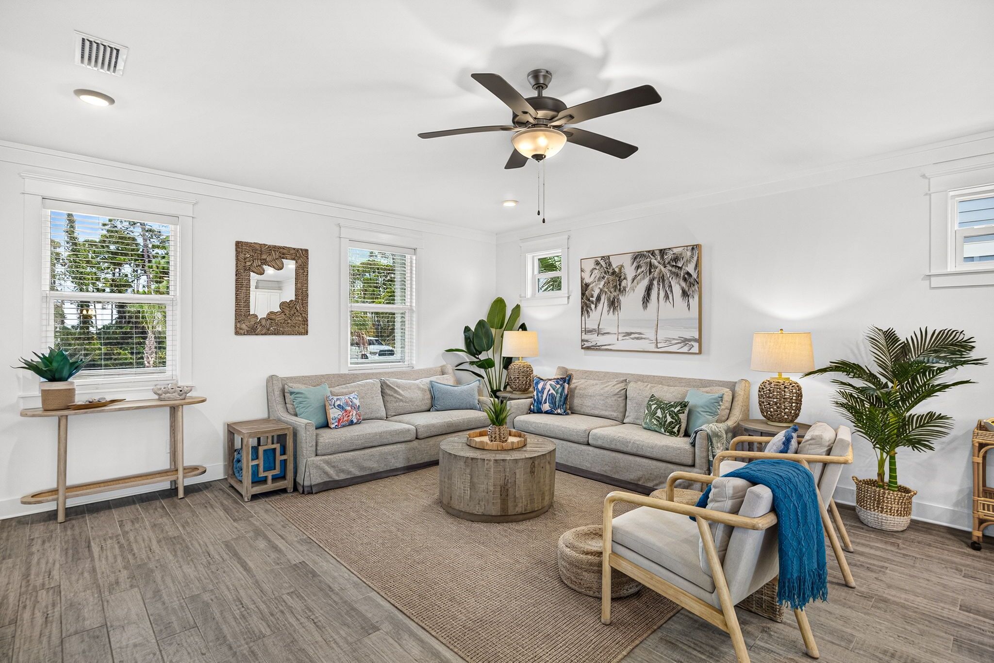 A modern living room with a sectional sofa, a round coffee table, and a ceiling fan.