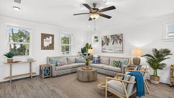 A modern living room with a sectional sofa, a round coffee table, and a ceiling fan.