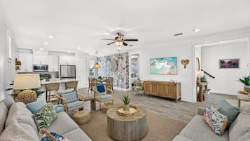 A modern living room with a sofa, chairs, a coffee table, and a dining area with a table and chairs.