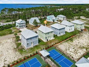 Un quartier résidentiel situé sur la côte, composé de plusieurs maisons à deux étages, d’un court de tennis et d’une plage.