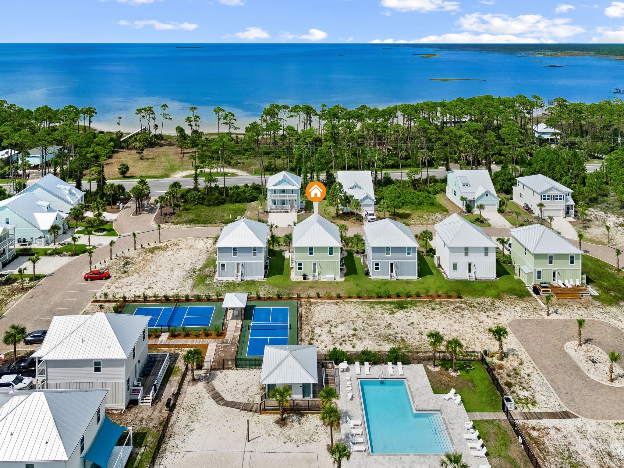 A coastal residential area with houses, a tennis court, and a swimming pool.