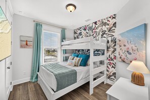 Ein Schlafraum mit Etagenbett, Fenster, Gemälde und Lampe.