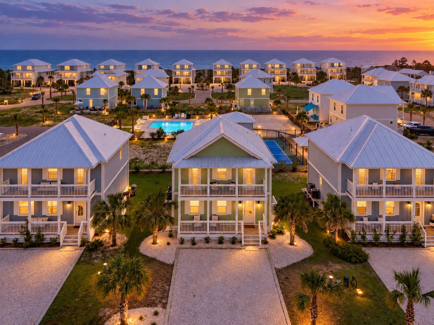 Un resort con múltiples villas frente al mar, una piscina y una cancha de tenis.