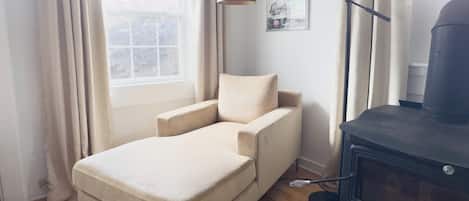 Ein kleines Zimmer mit einem Bett, einem schwarzen Heizkörper, einer Stehlampe und einem fenster mit Vorhängen.