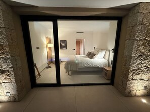 A bedroom with a bed, bedside tables, a lamp, and a door leading to another room. - New contemporary villa with pool—5 bedrooms with en suite bathrooms—Ste Lucie de PV (Sainte Lucie de Porto Vecchio)