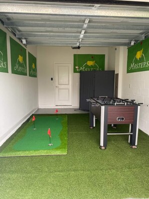Habitació amb taula de futbolí, gespa artificial i una porta.