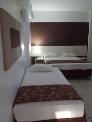 Une chambre d’hôtel avec deux lits, une table de chevet et une lampe fixée au mur.
