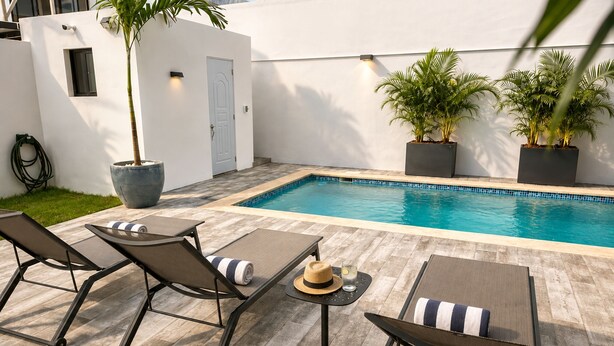 A poolside area with lounge chairs, a small table, and potted plants. - Private Pool Villa 3BR Gated 10 Min Downtown (Punta Cana)