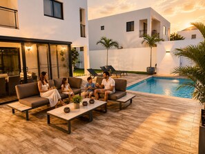 A modern outdoor seating area with a pool, lounge chairs, and a dining table. - Private Pool Villa 3BR Gated 10 Min Downtown (Punta Cana)