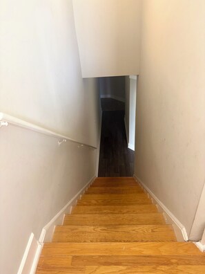 A wooden staircase with white walls and a dark floor leading to a room. - Game Day Get Away! Steps From Mercedes Benz stadium! (Atlanta)