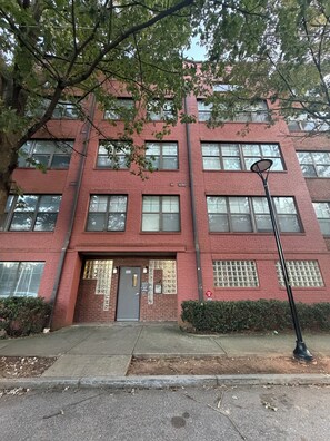 A red brick building with multiple windows, a door, and a street lamp. - Game Day Get Away! Steps From Mercedes Benz stadium! (Atlanta)
