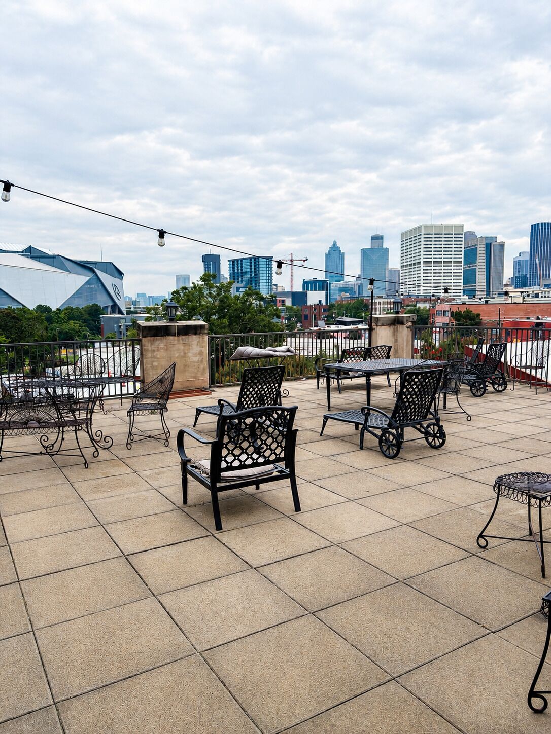 A rooftop terrace with outdoor seating, a city skyline in the background, and a clear sky.