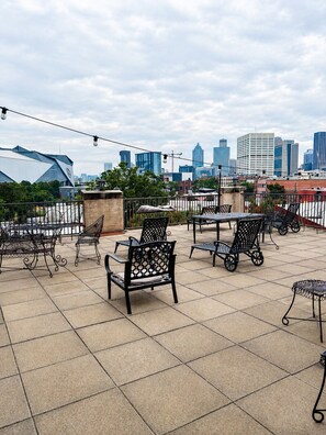 Una terraza en la azotea con asientos al aire libre, un horizonte urbano al fondo y cielo despejado.