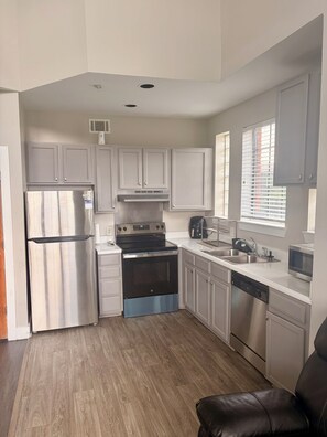 A compact kitchen with a refrigerator, stove, oven, and dishwasher. - Game Day Get Away! Steps From Mercedes Benz stadium! (Atlanta)