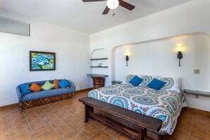 A bedroom with a bed, a bench, a sofa, and a wall-mounted shelf.