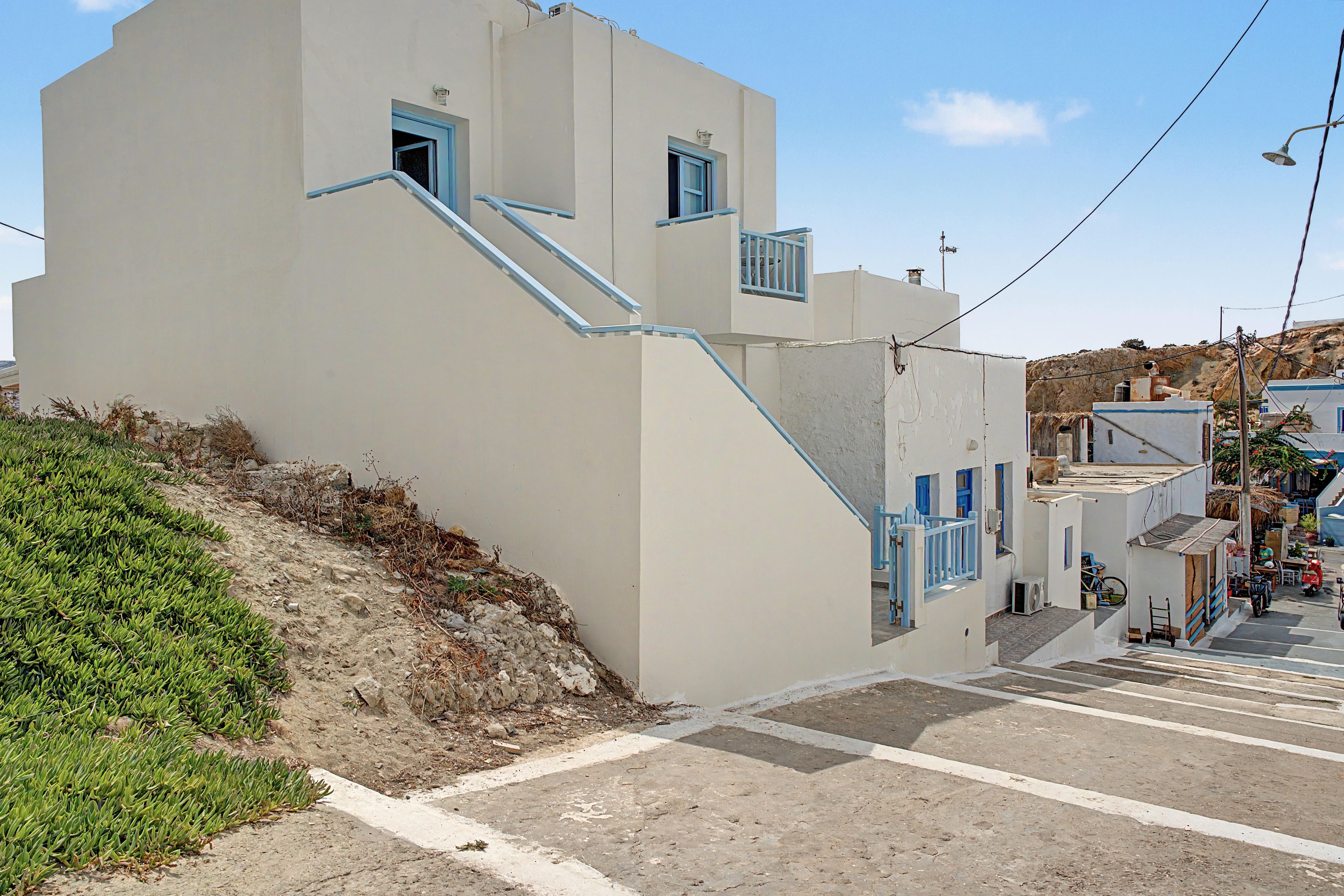 Un edificio con una escalera empinada, un ventanal pequeño y una puerta.