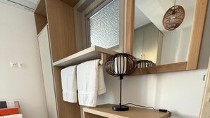 Uma casa de banho moderna com lavatório de madeira, candeeiro pendente e porta-toalhas.