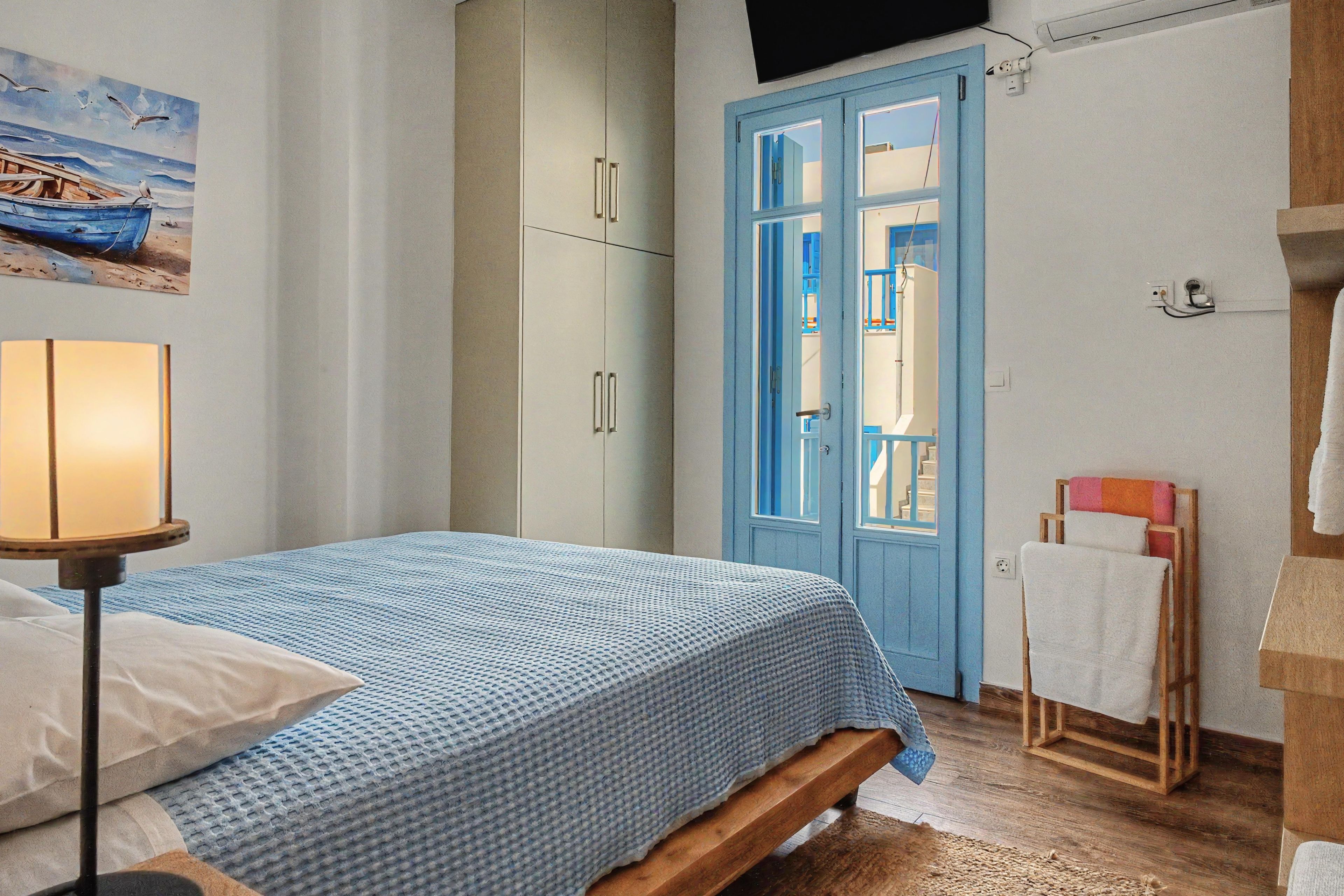 A bedroom with a bed, a wardrobe, a door leading to a balcony, and a painting on the wall.