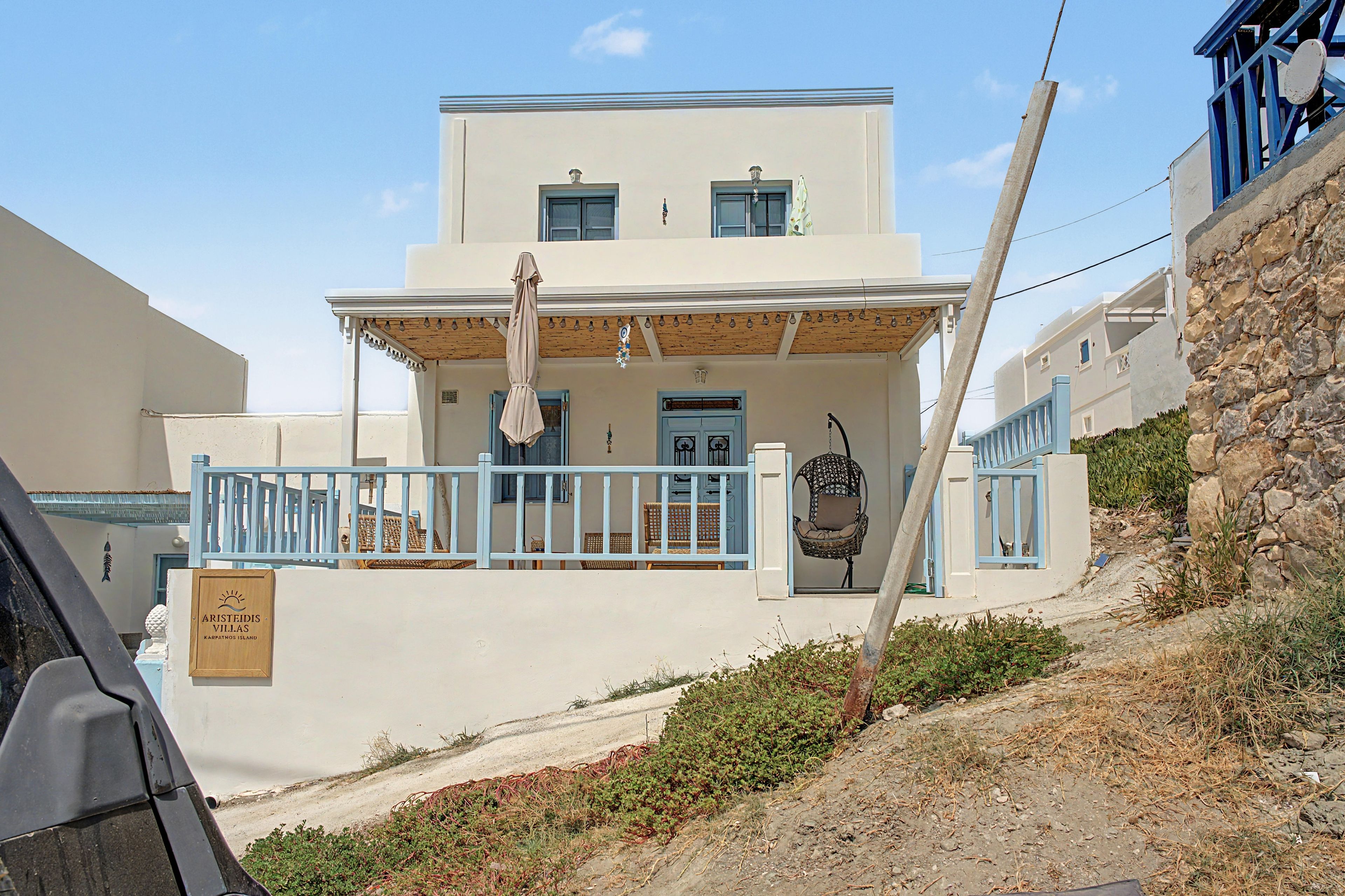 A two-story building with a balcony, a signboard, and a stone wall.
