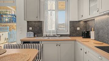 A modern kitchen with a built-in dishwasher, a coffee machine, and a view through a window with a lace curtain.