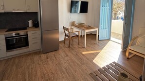 Una cocina moderna con horno empotrado, refrigerador y comedor con mesa y sillas.