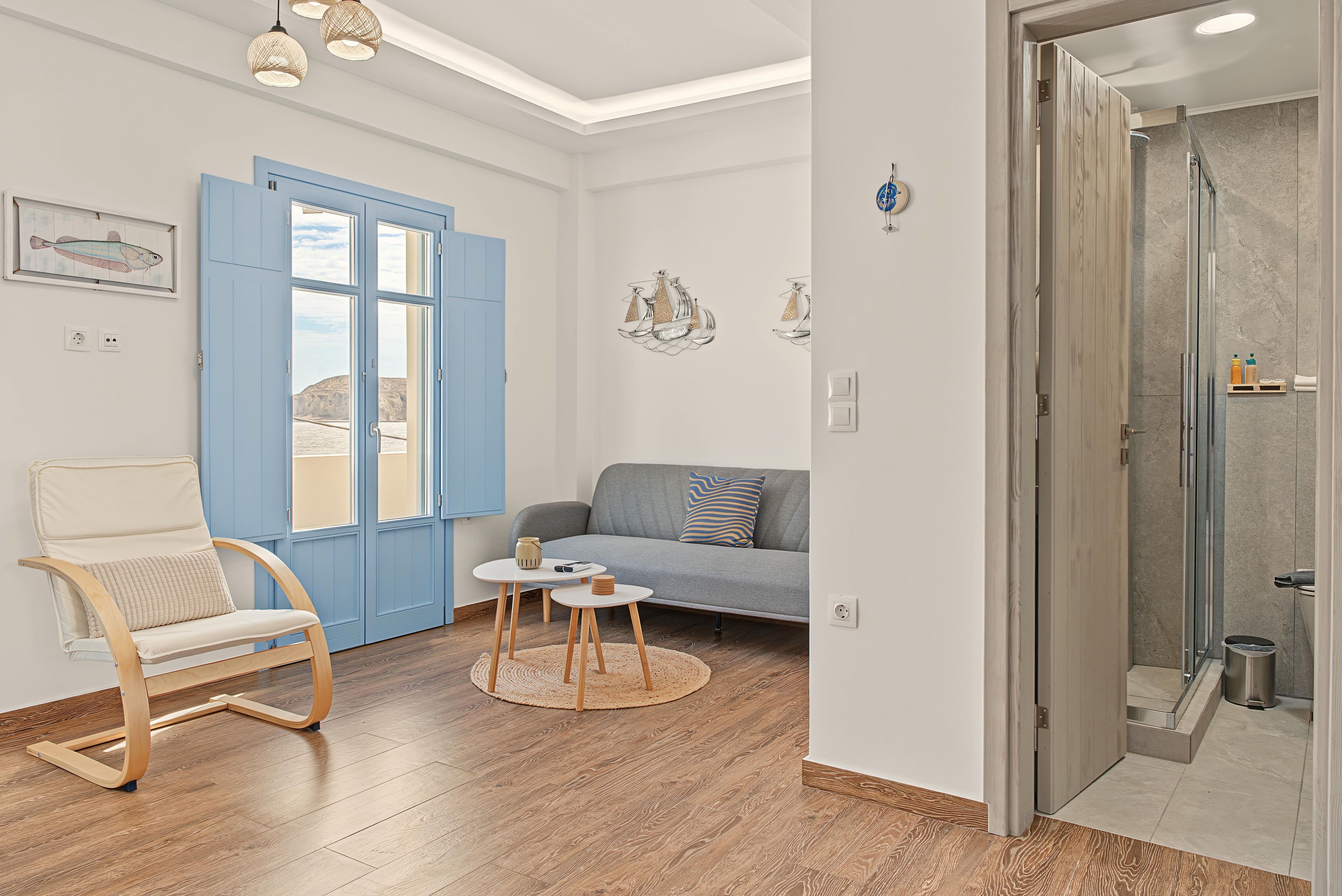 Ein modernes Wohnzimmer mit einer blauen Tür, einem grauen Sofa, einem Holzstuhl und einem kleinen runden Tisch.