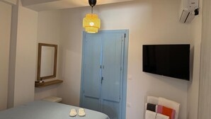 Un dormitorio con cama, un armario azul, televisor y espejo.