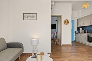 A modern living room with a sofa, a lamp, a coffee table, and a kitchen in the background.