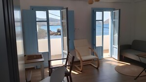 Une pièce avec vue sur la mer, un plancher en bois, une chaise blanche et un canapé.
