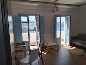 Una stanza con vista sul mare, pavimento in legno, una sedia bianca e un divano.