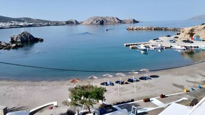 Une plage côti ère avec un port de plaisance, des parasols et des chaises longues.