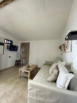 A living room with a sofa, a coffee table, a TV, and a curtain.