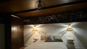 Une chambre à coucher comprenant un lit, deux tables de chevet, un luminaire suspendu et une armoire.